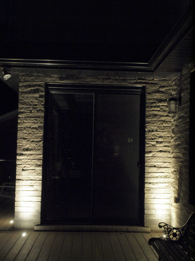 A patio at night with a bench and lights.