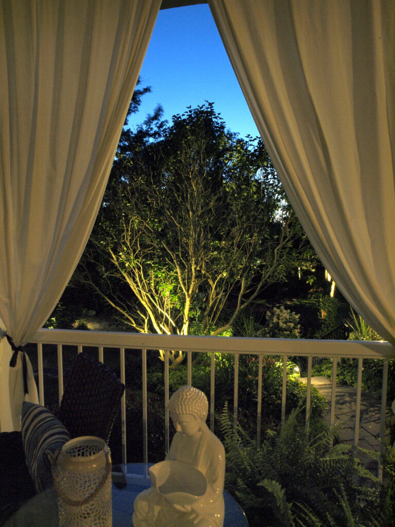 A balcony with a lit up tree and a Buddhist statue.