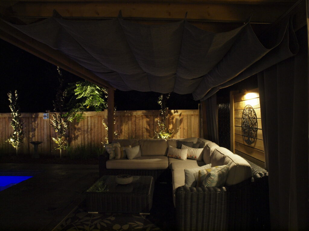 A wicker sectional couch in a backyard at night.