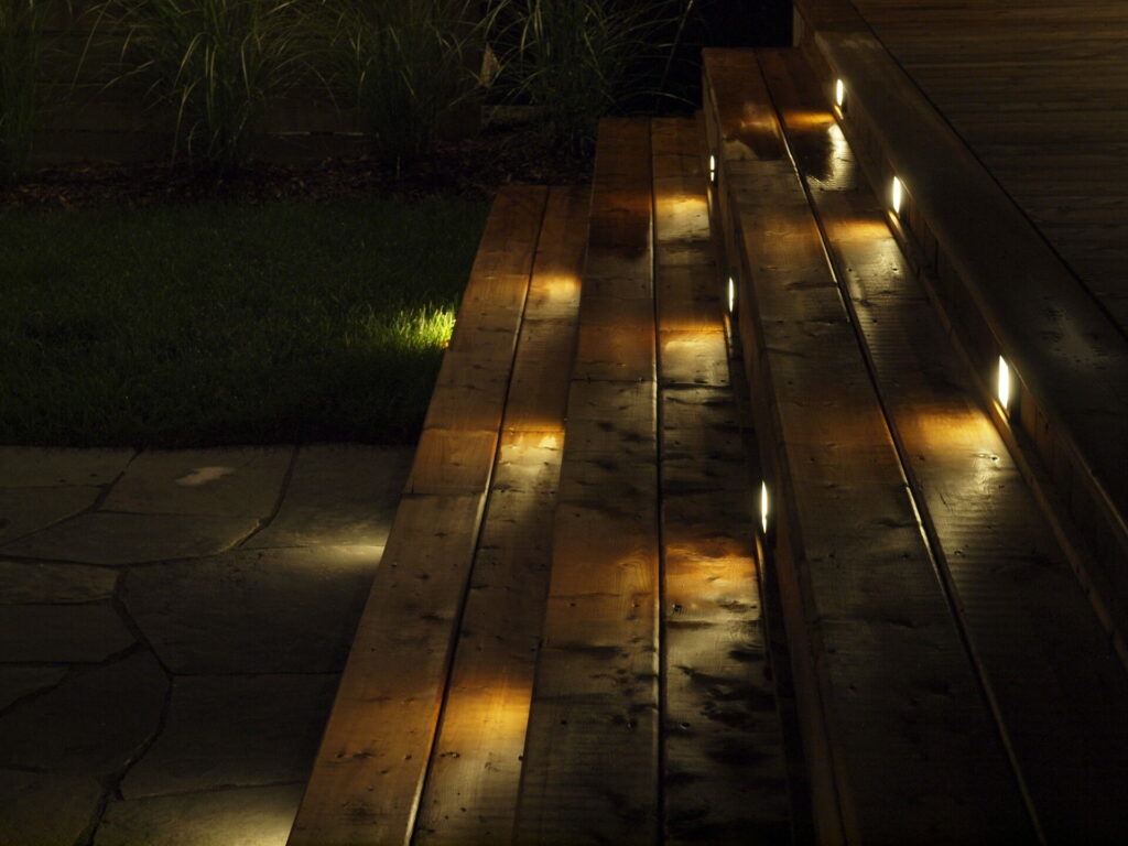 Wooden stairs lit up with outdoor lighting at night.