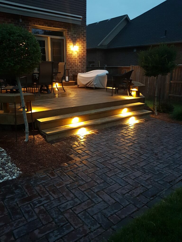 A deck with lighting and steps at night.