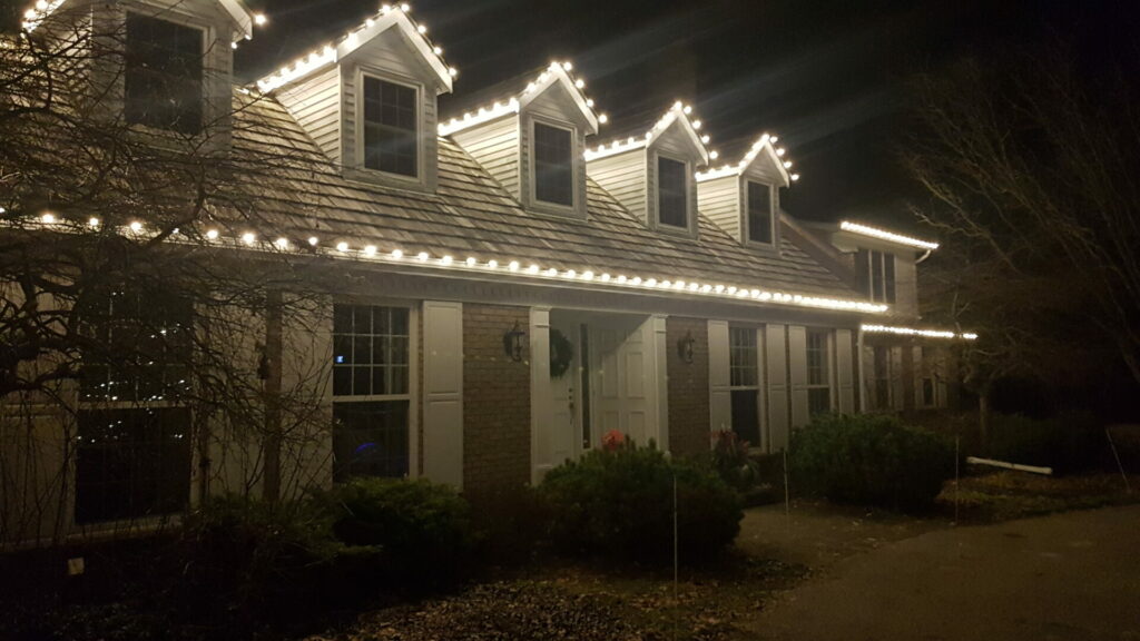 A house is lit up at night with Christmas lights and outdoor lighting.