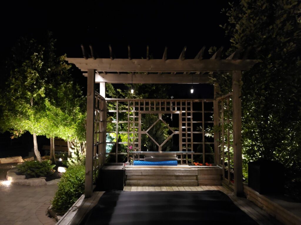 A garden at night with a wooden pergola.