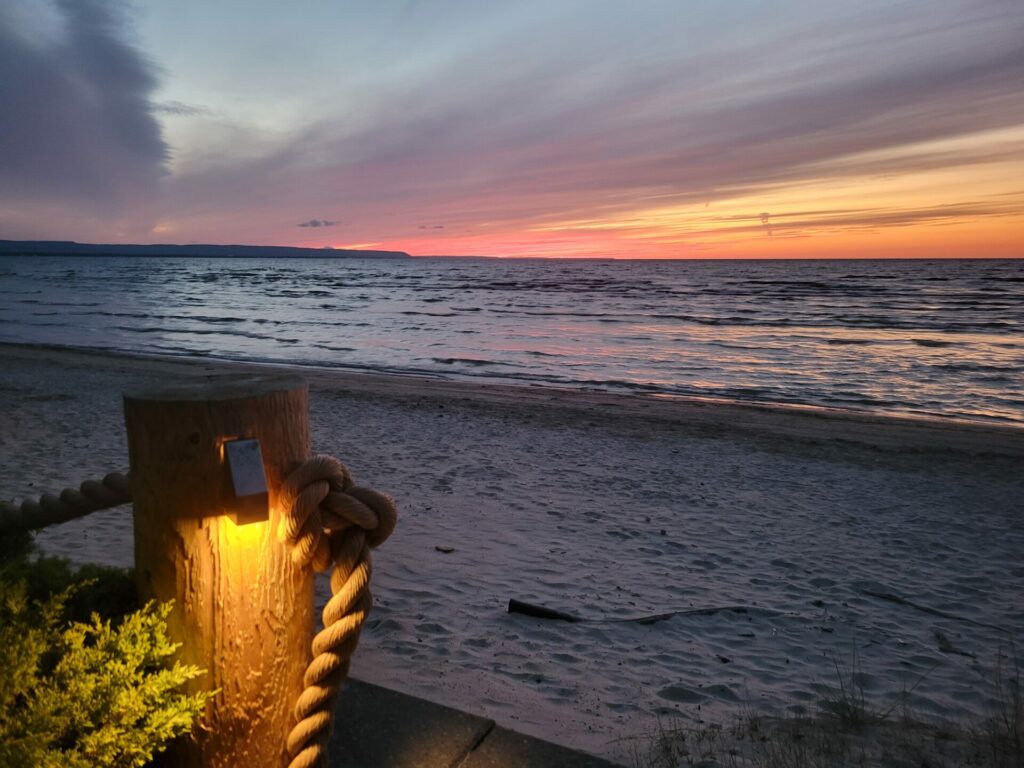 A wooden post on the beach at sunset.