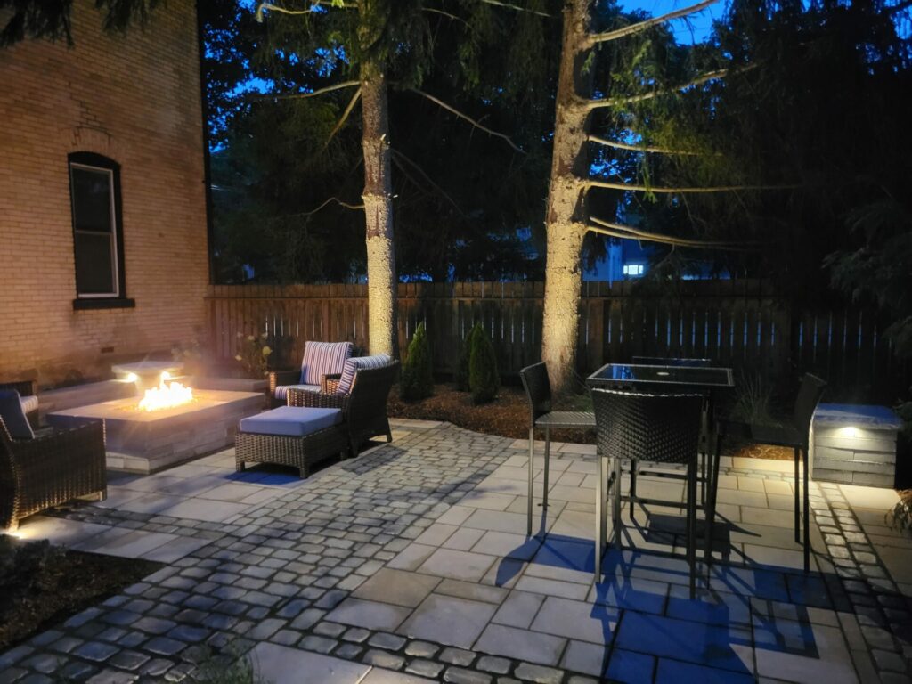 A patio with a fire pit and chairs at night.