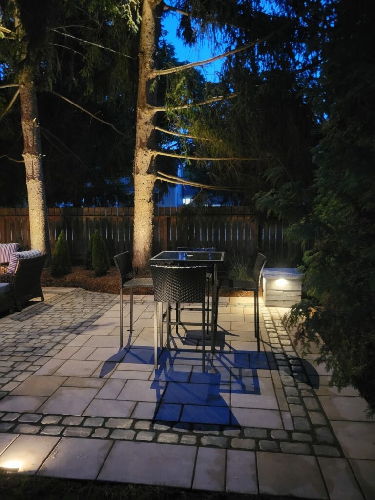 A patio with outdoor furniture and lighting at night.