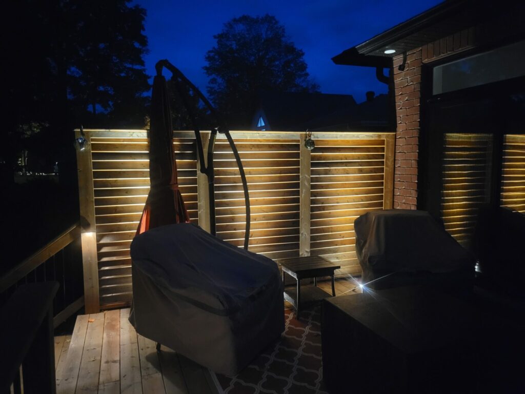 A wooden deck at night with a table and chairs.