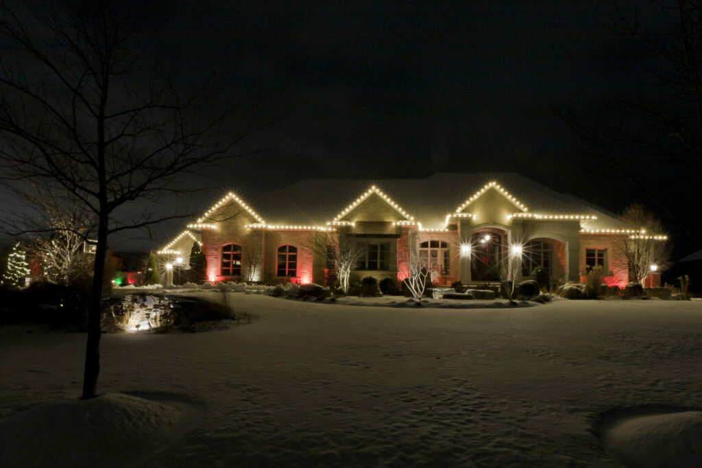 A house is lit up with Christmas lights in the snow.