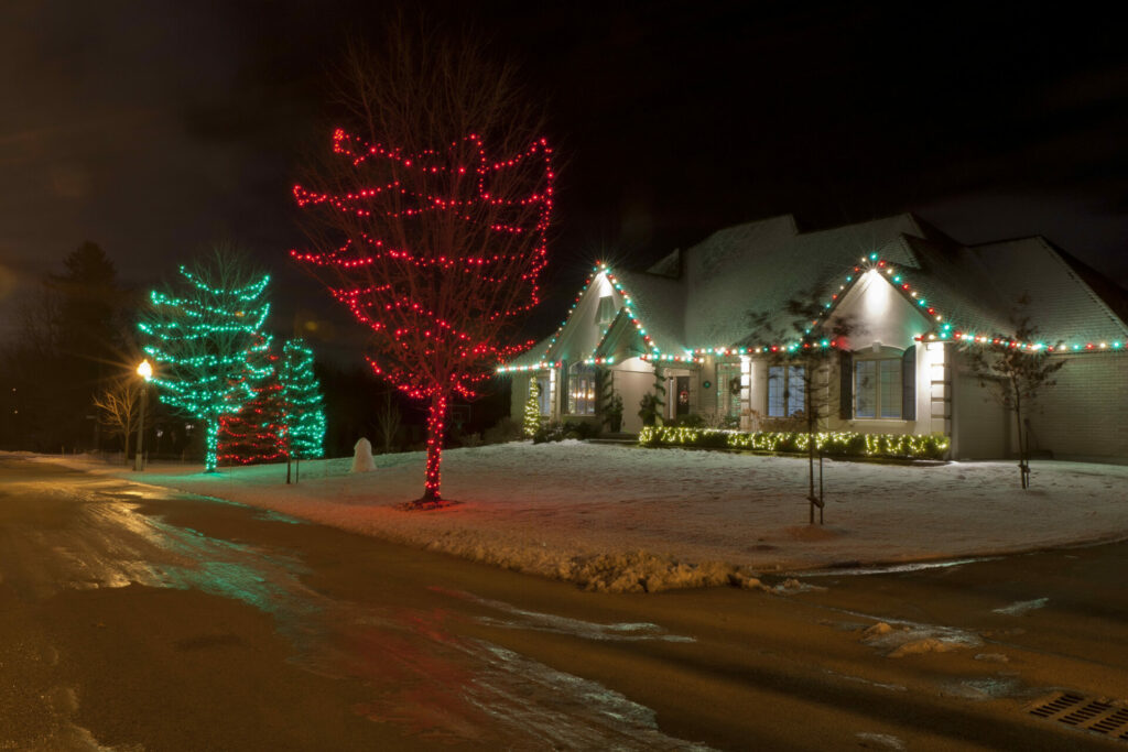 A house is lit up at night with outdoor lighting and Christmas lights.