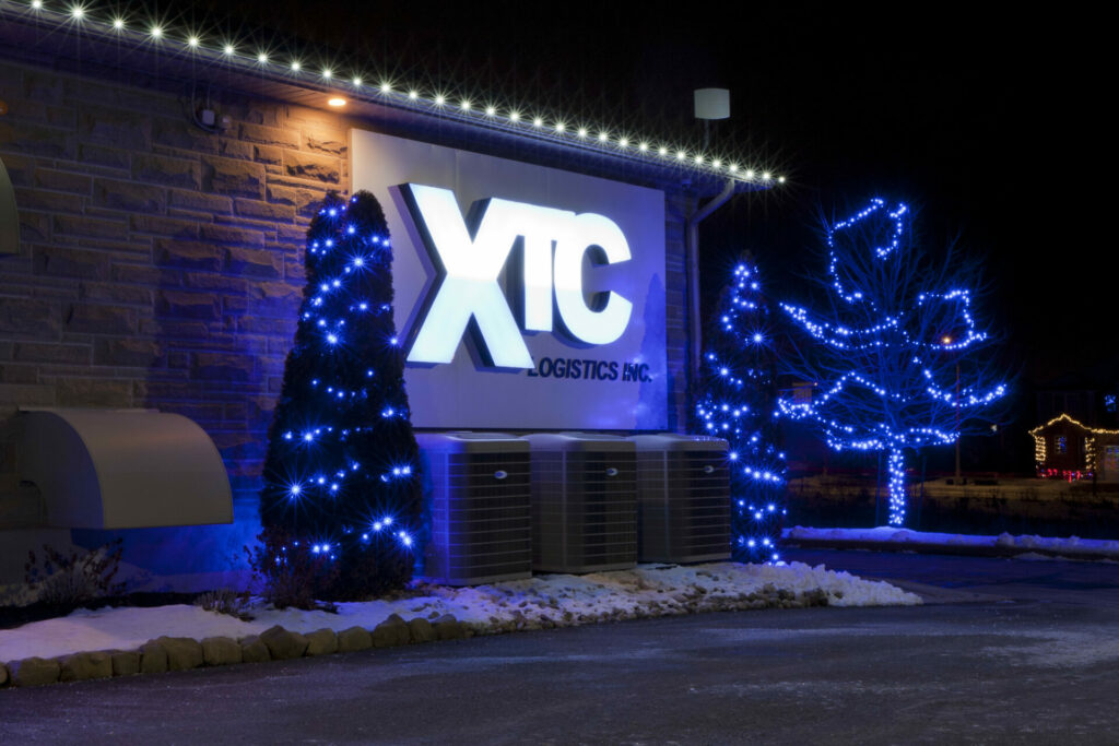 The xtc building is lit up with blue holiday lights on trees.