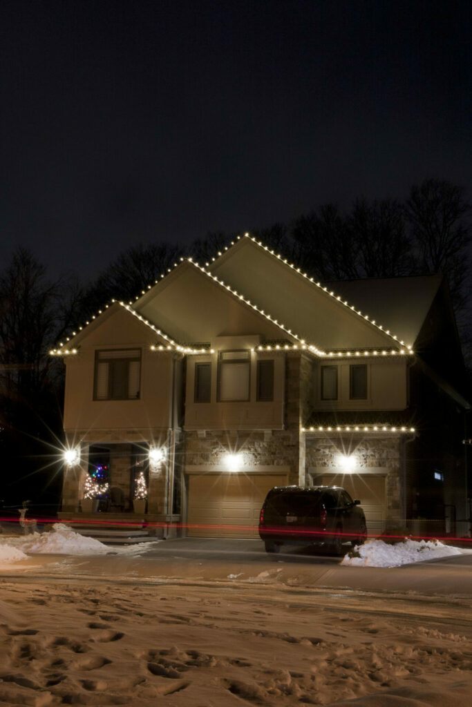 A house is lit up at night with Christmas lights and outdoor lighting.