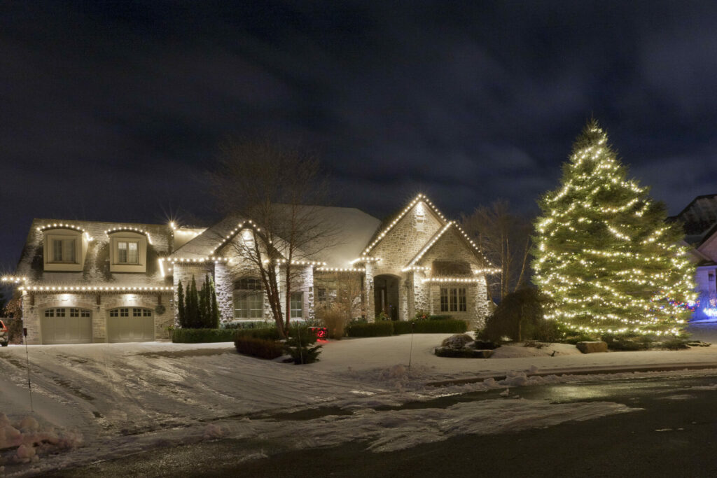 A large house is lit up at night with Christmas lights and outdoor lighting.