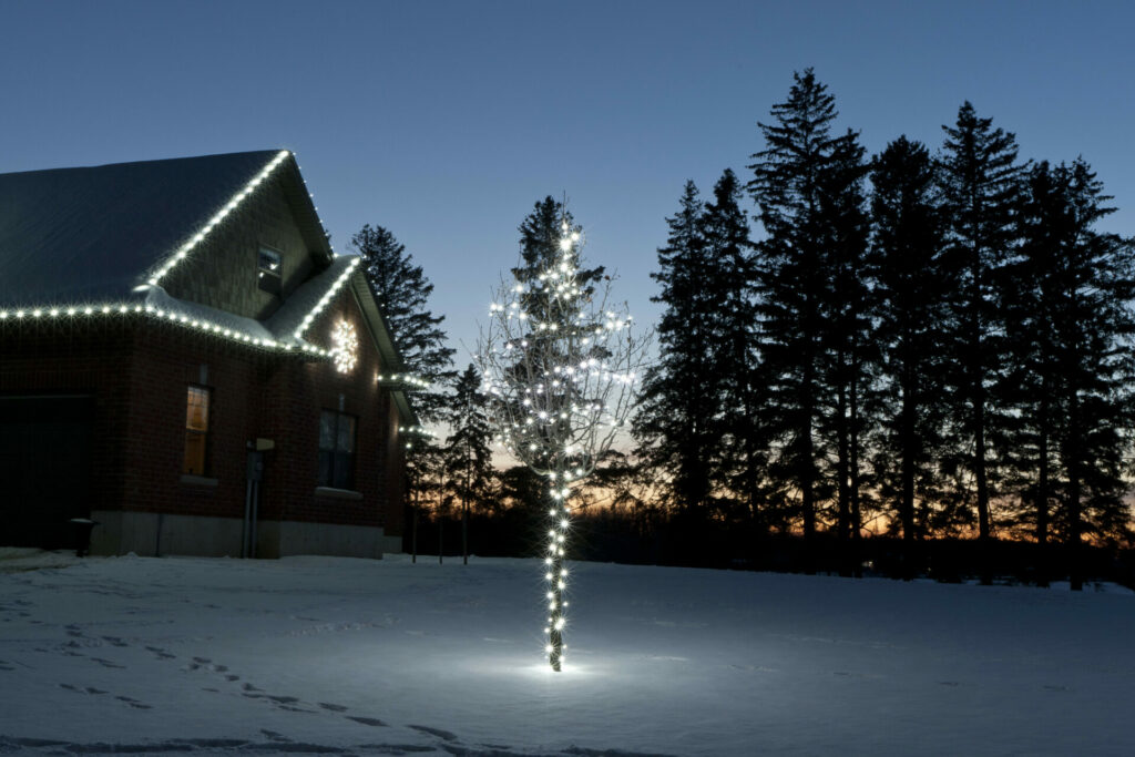 A house is lit up at night with Christmas lights and outdoor lighting at sunset.