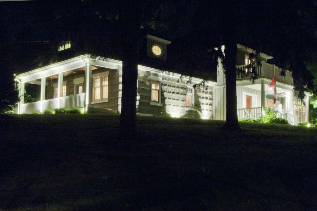 A large white house lit up at night.