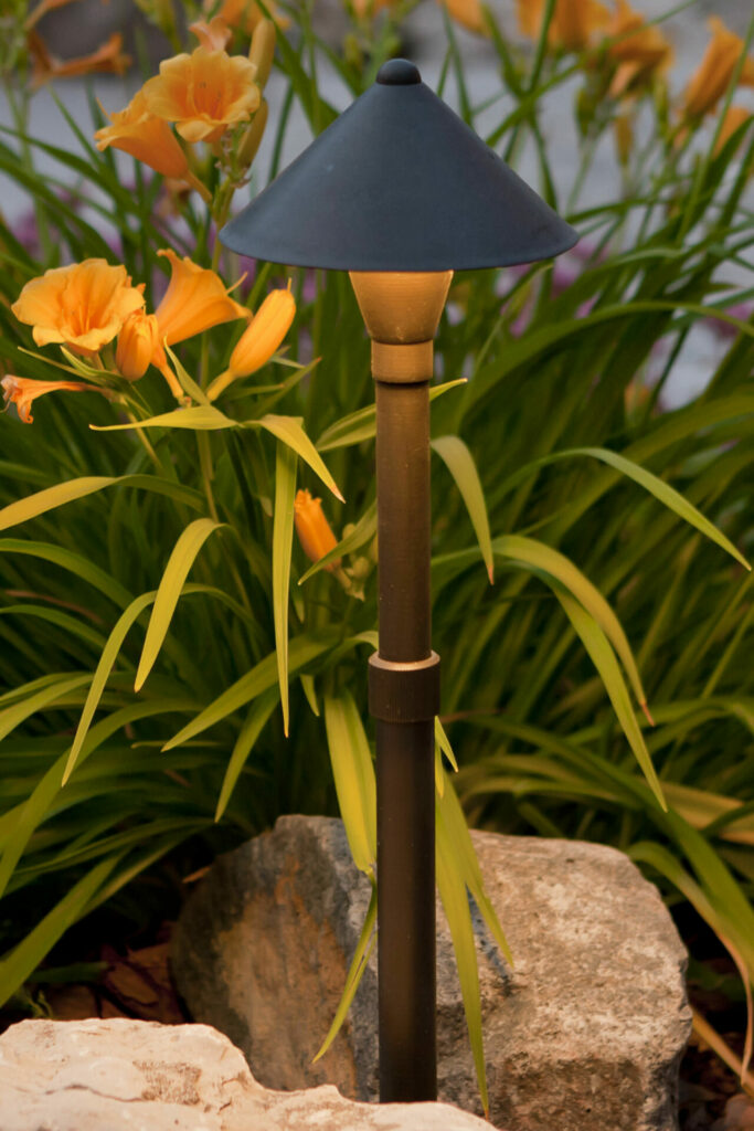 A black lamp in a rock and flower garden.