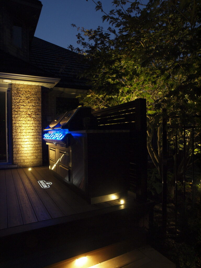 A deck with a grill on it lit up at night.