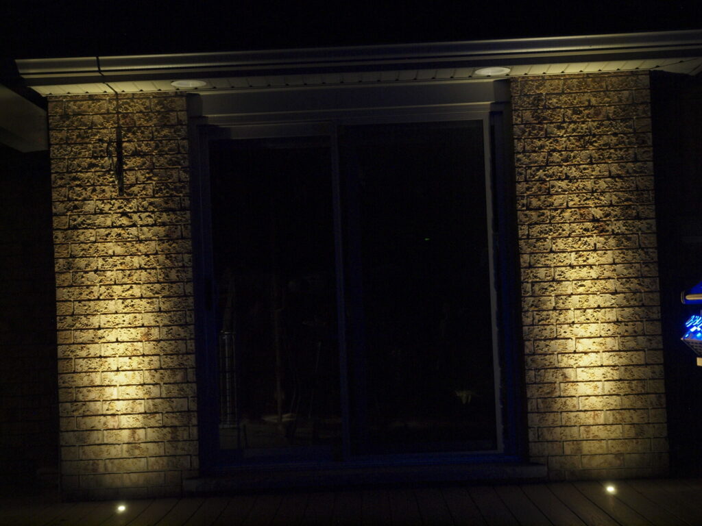 A brick wall and window with outdoor lights on it at night.
