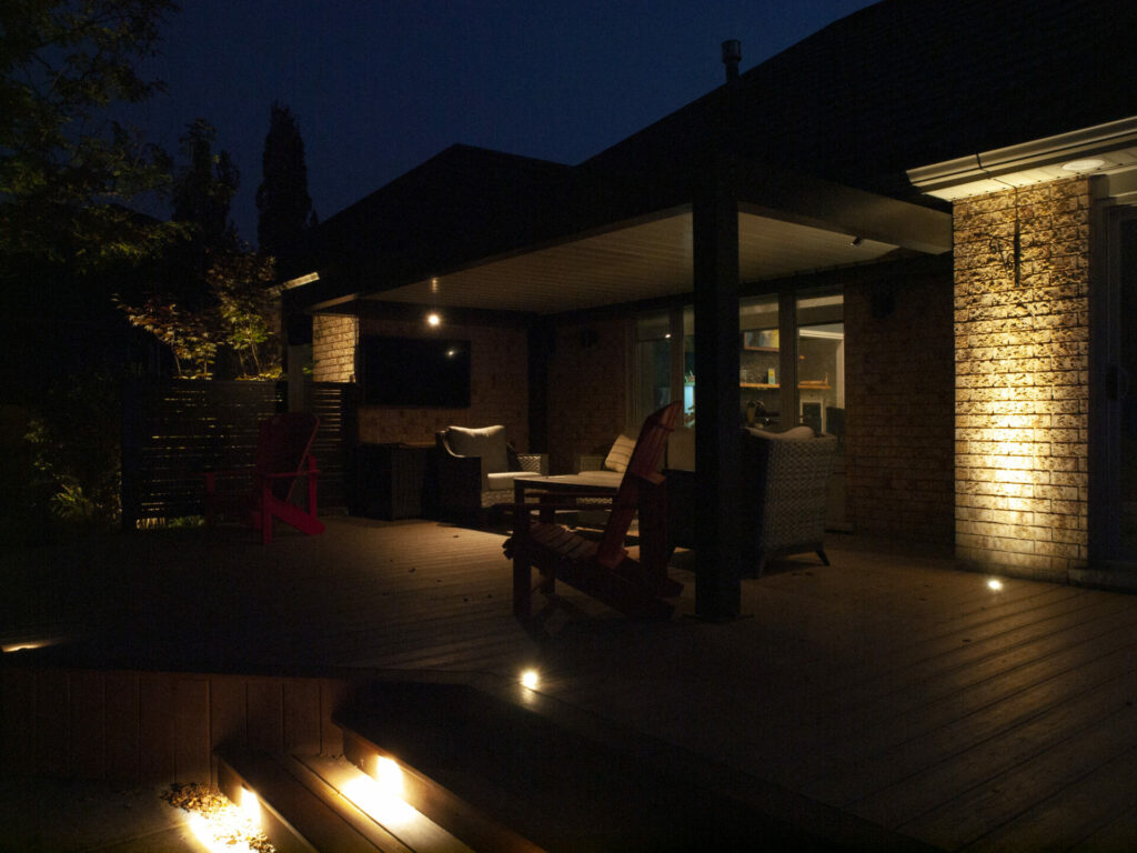 A deck lit up at night with patio furniture.