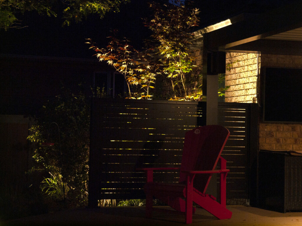 A red chair in a yard at night lit up by outdoor lighting.