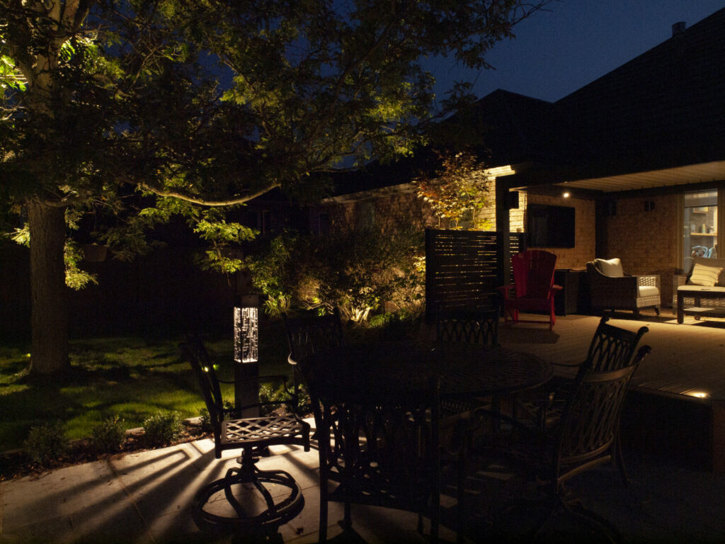 A backyard with lots of outdoor seating lit up at night.
