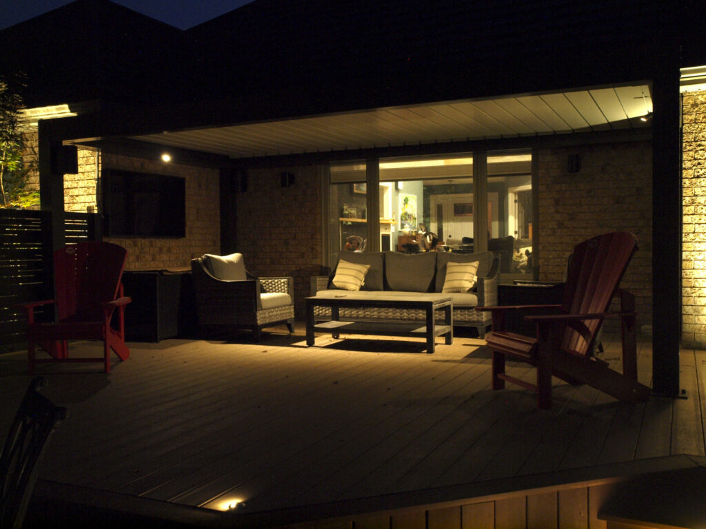 A deck with outdoor furniture is lit up at night.