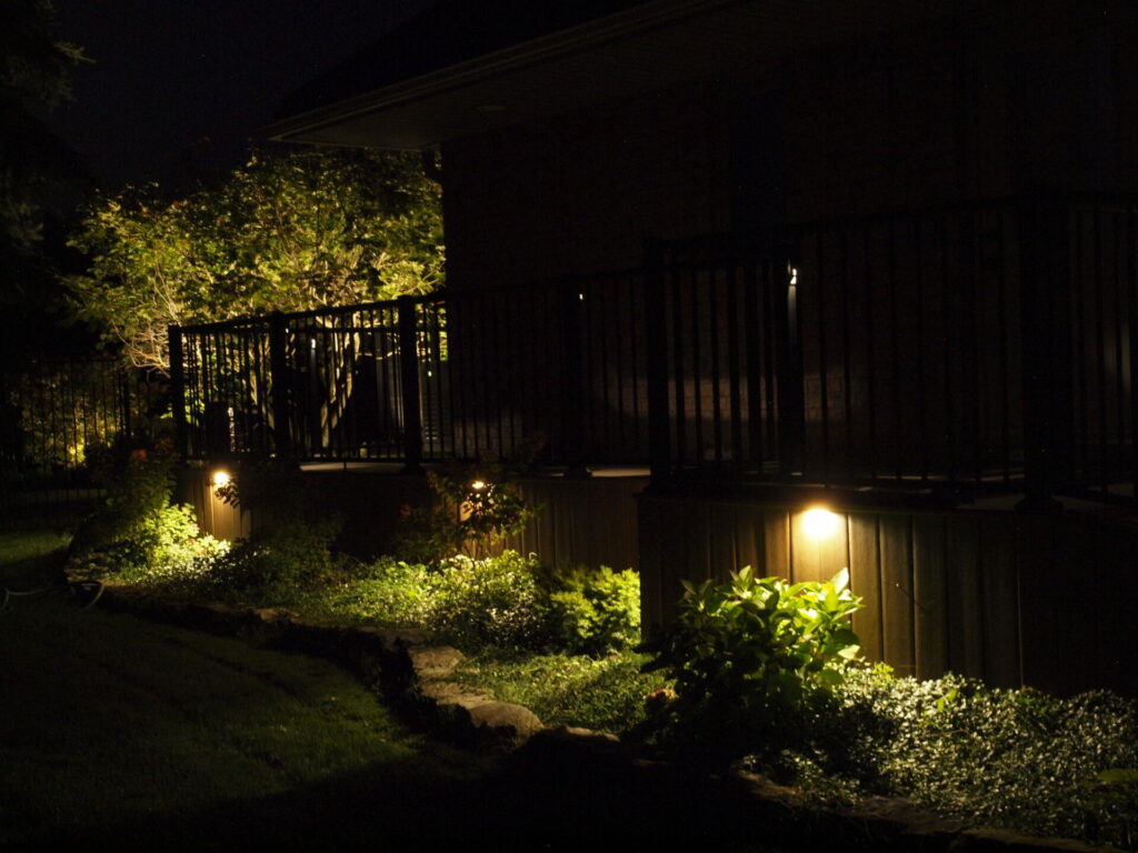 A house with a garden at night lit up by outdoor lighting.