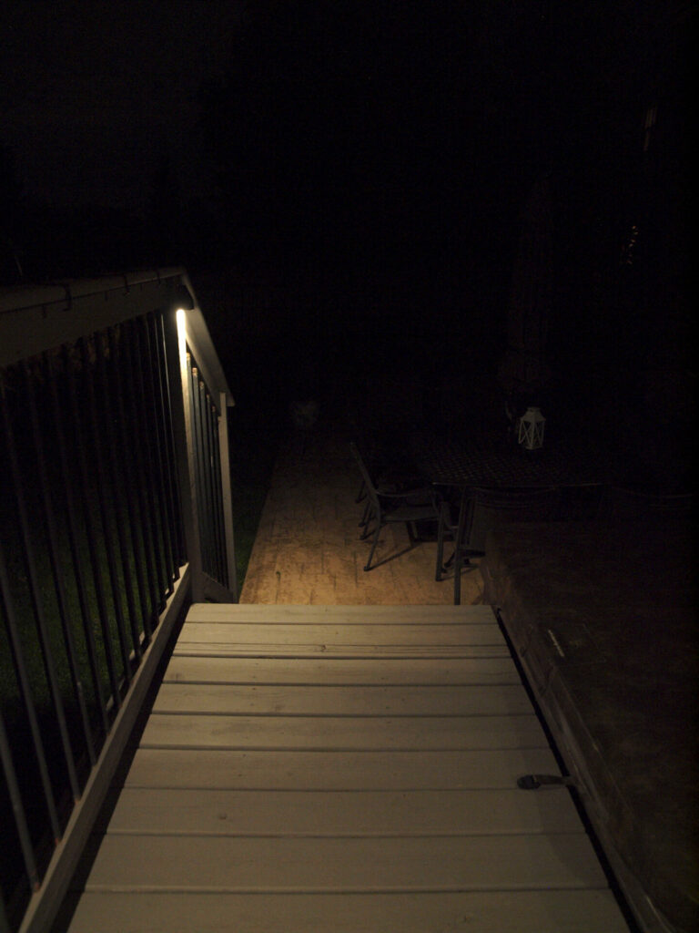 A wooden stairway with outdoor lighting in the dark.