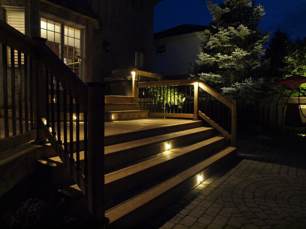 A deck with stairs and lighting at night.