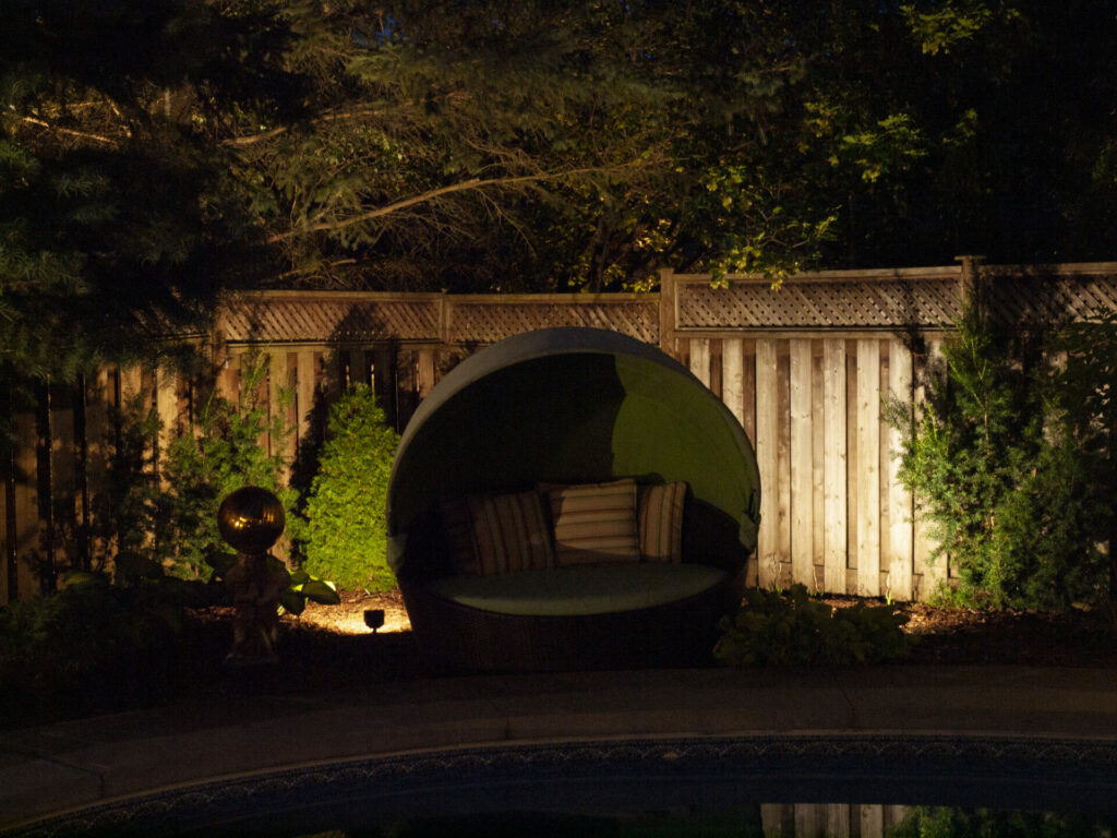 A large, round seat and a wooden fence in a backyard at night.