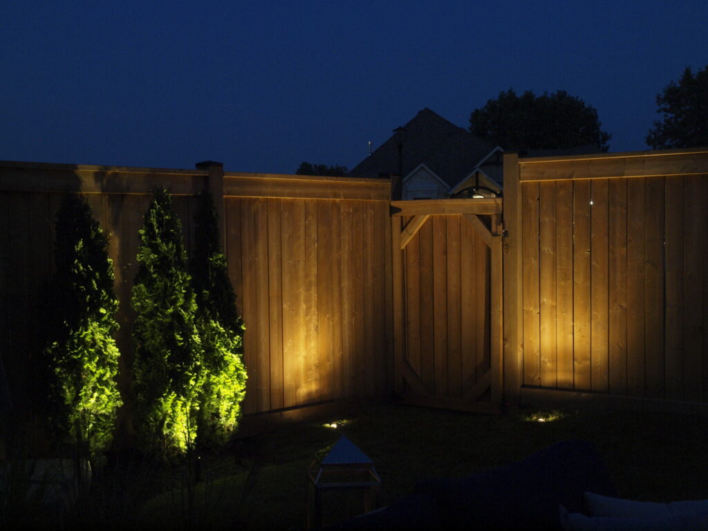 A wooden fence is lit up at night.