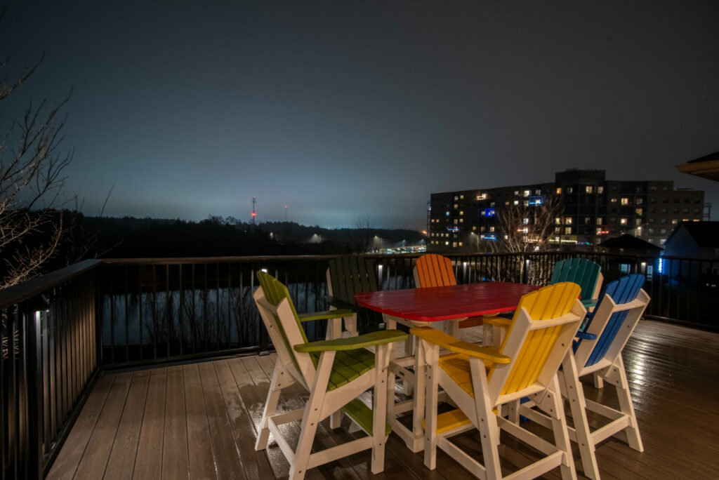 A deck with colorful chairs and a table at night.
