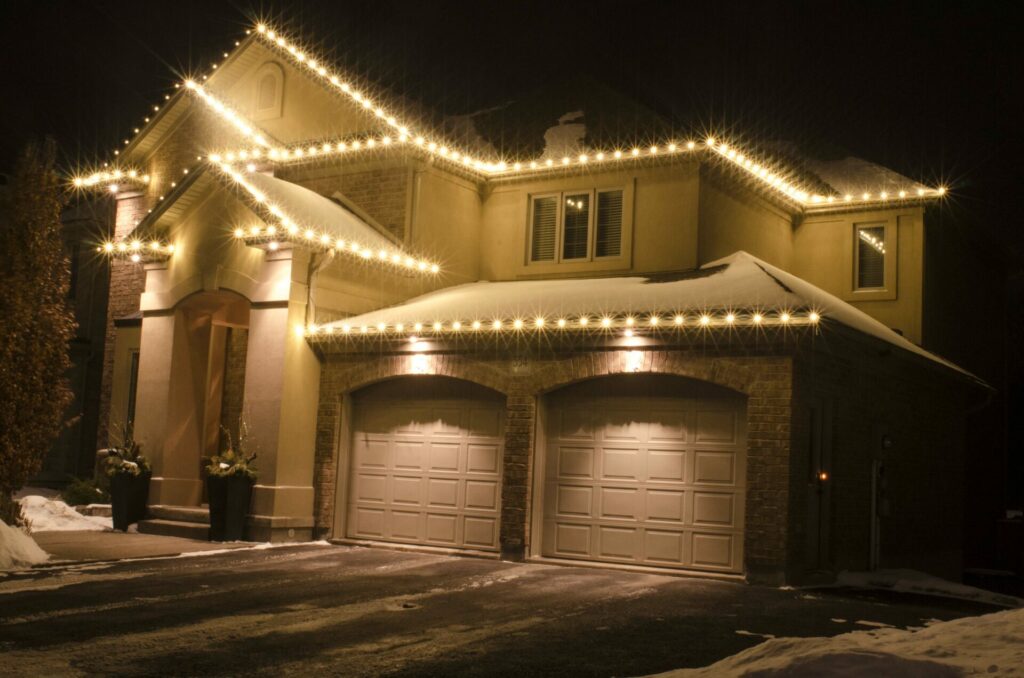 A house is brightly lit up at night with outdoor lighting and Christmas lights.