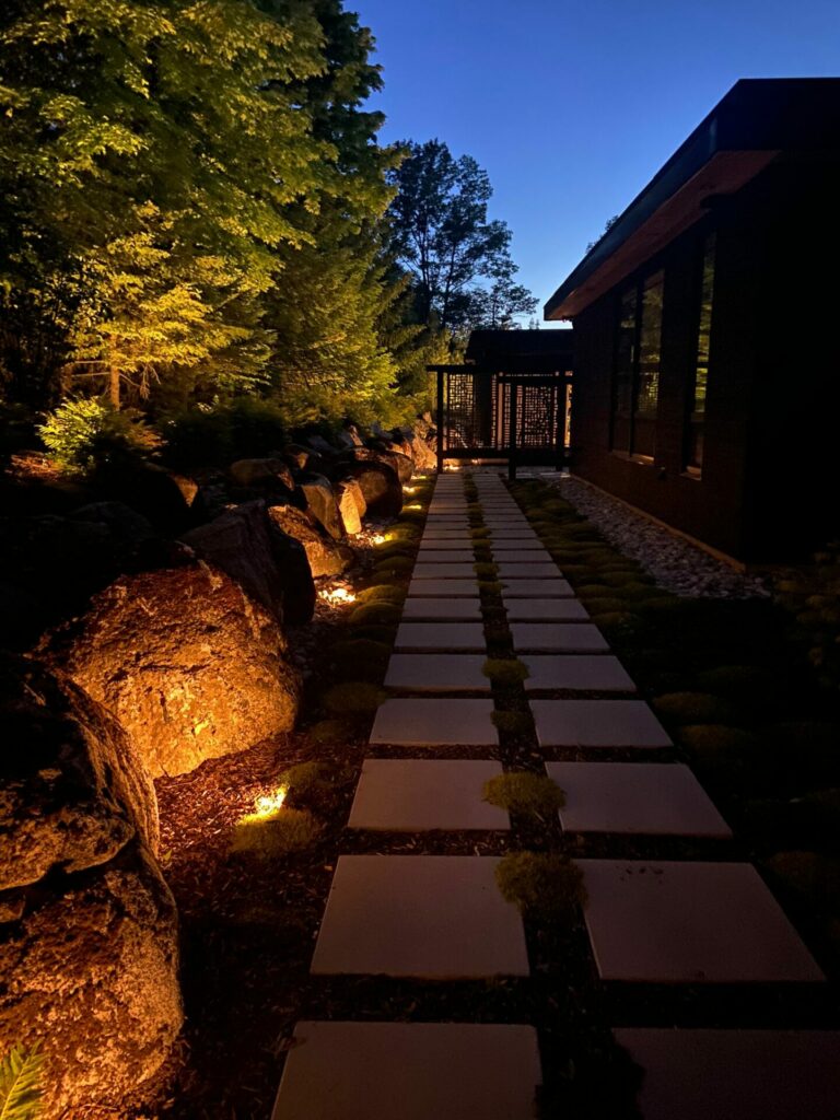 A pathway lit up at night with rocks and lighting.