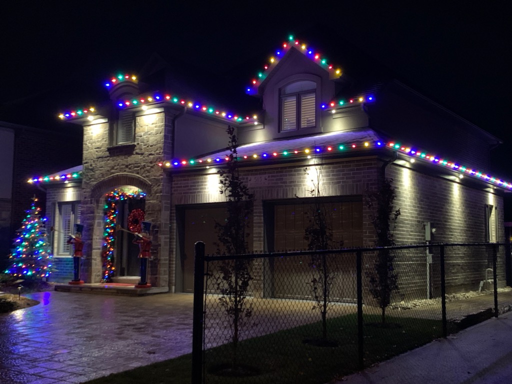 A house is lit up with Christmas lights and outdoor lighting at night.