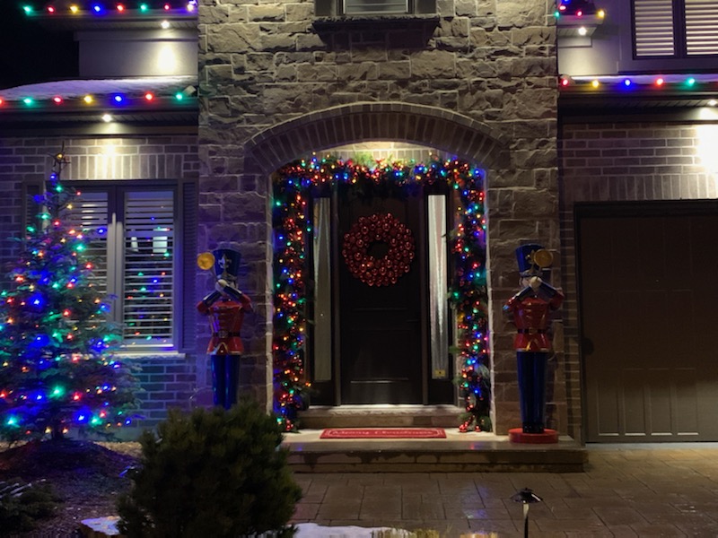 A house with Christmas lights and big nutcracker decorations in front of it.