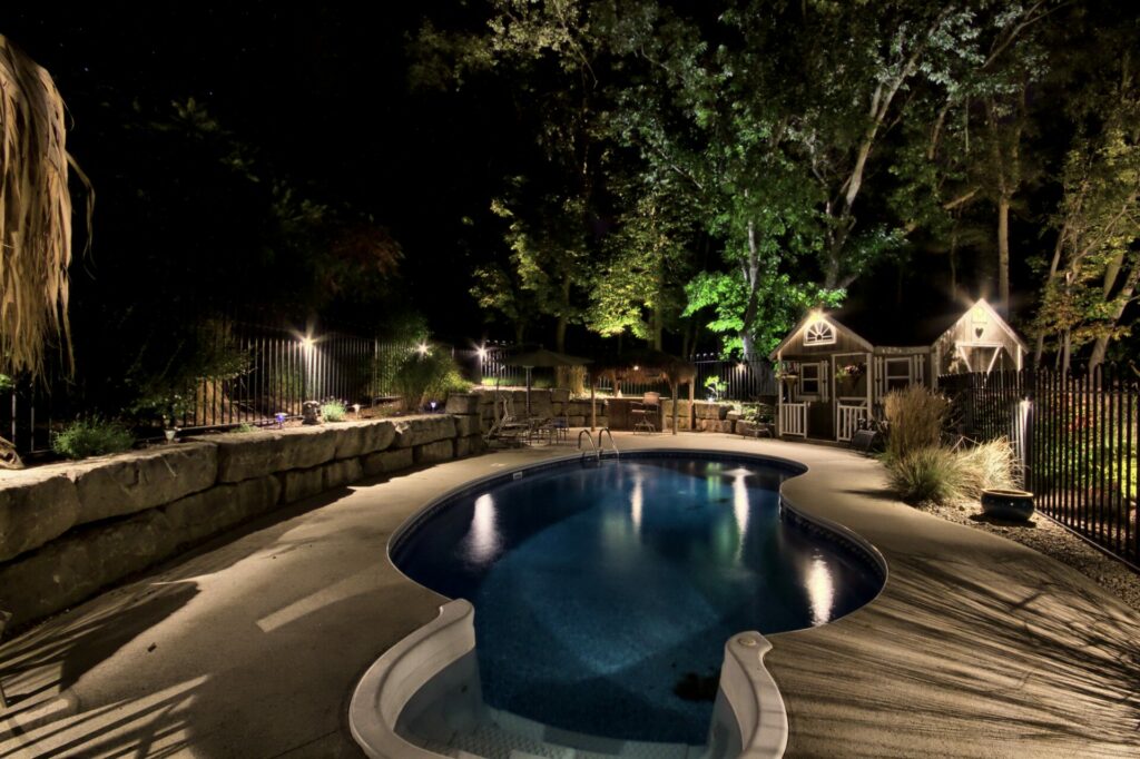 A pool with a deck and a fence at night.