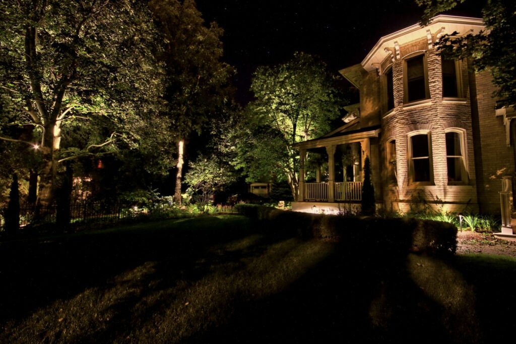 A house is lit up at night with trees in the background.