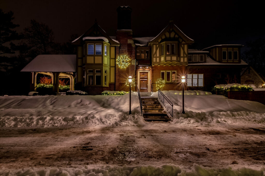 A large house is lit up at night in the snow.
