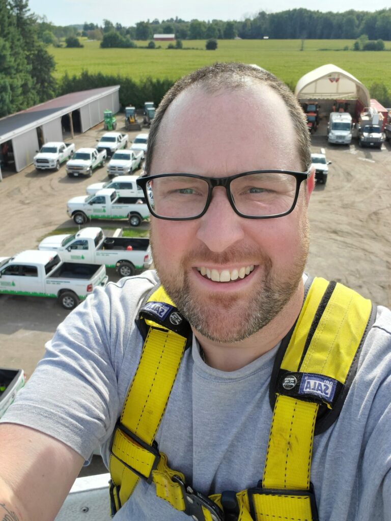 A happy man taking a selfie in front of a bunch of trucks from above.