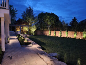 A backyard lit up at night with outdoor lighting.