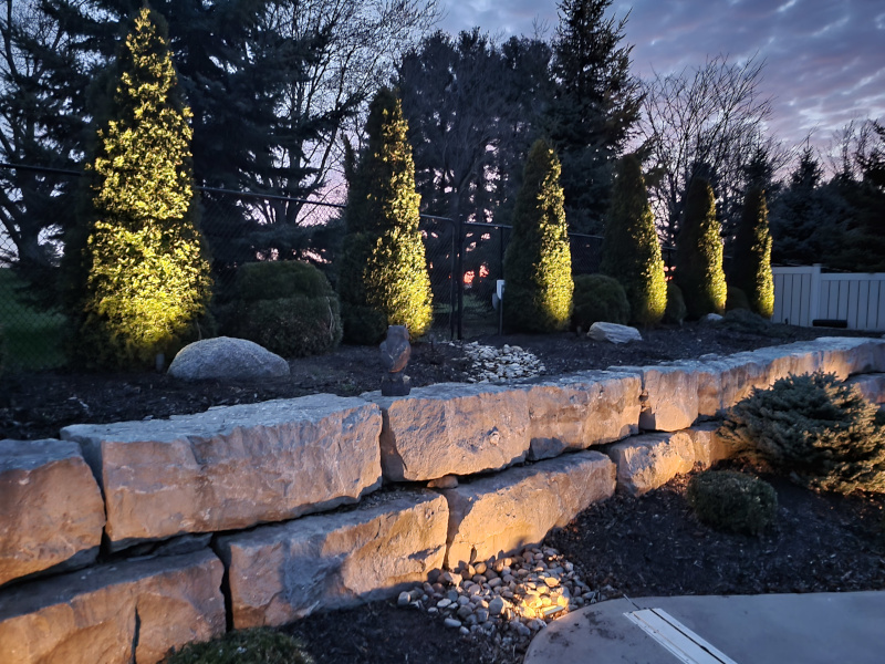 A stone wall is lit up at dusk.